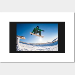 Snowboarder jumping against blue sky Posters and Art